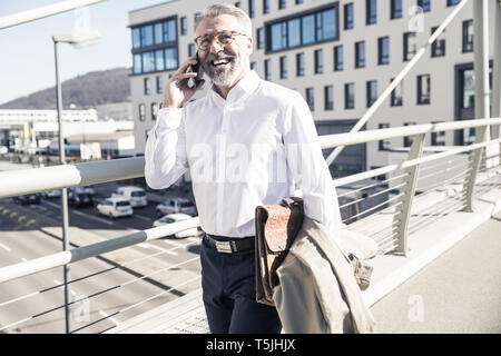 Happy mature businessman talking on cell phone in the city Stock Photo