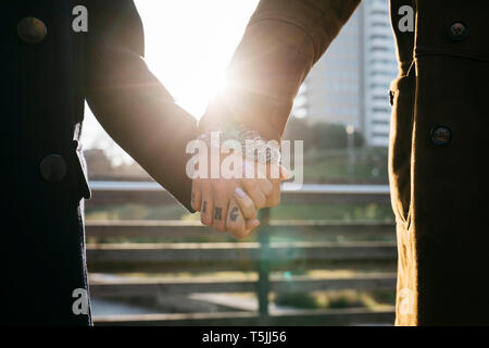 Close-up of couple holding hands in backlight Stock Photo