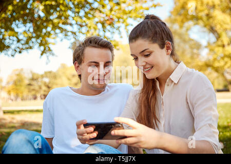 Young couple looking at smartphone in a park Stock Photo