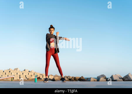 Sportive young woman during workout, stretching arm Stock Photo