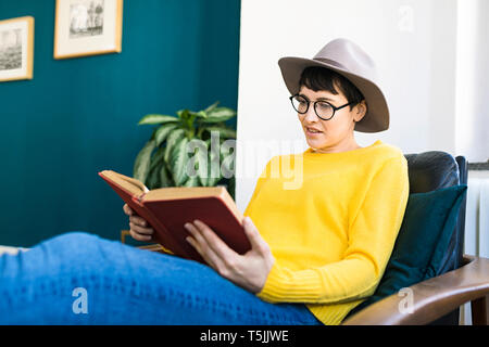 Woman relaxing in lounge chair reading a book Stock Photo