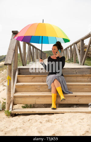 Woman with colorful umbrella standing on the beach Stock Photo