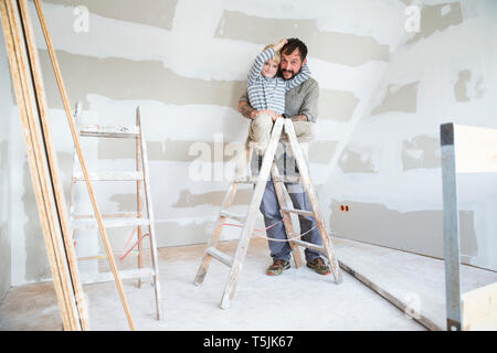 Portrait of happy father and son working on loft conversion Stock Photo