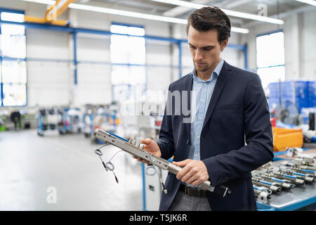 Businessman examining workpiece in a factory Stock Photo