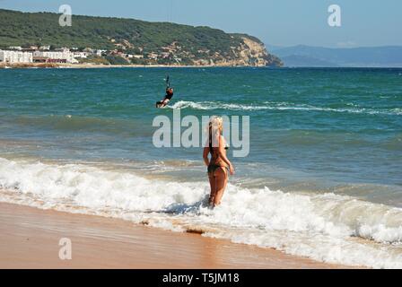 Woman paddling in the sea with a kitesurfer to the rear, Cabo Trafalgar, Cadiz Province, Andalusia, Spain, Europe. Stock Photo