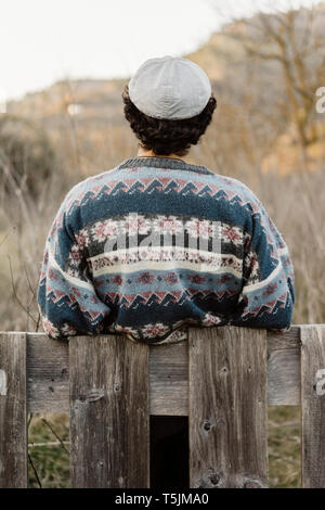 Young man leaning on fence, looking at view Stock Photo
