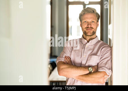 Portrait of confident casual man leaning against door case at home Stock Photo