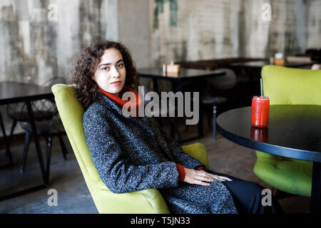 Young attractive girl sits in a cafe and drinks juice. Stock Photo