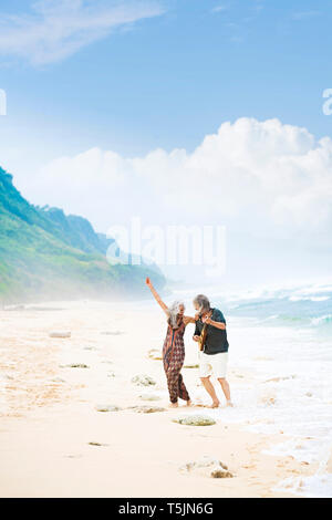 Happy senior hippie couple with guitar dancing on the beach Stock Photo