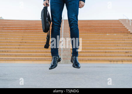 Legs of fashionable young man with backpack jumping in the air Stock Photo