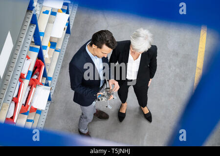 Businessman and senior businesswoman examining workpiece in a factory Stock Photo