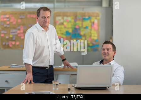 Portrait of two confident businessmen with laptop in office Stock Photo
