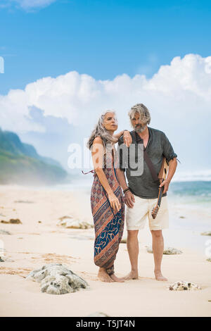 Senior hippie couple with guitar standing on the beach Stock Photo