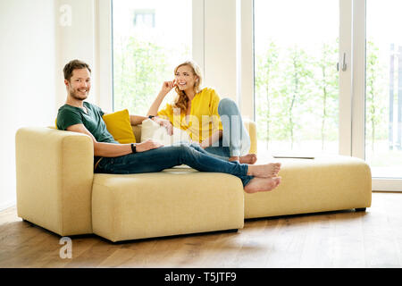 Couple sitting on couch in their new home, discussing Stock Photo
