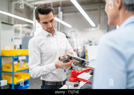 Businessman and senior businesswoman examining workpiece in a factory Stock Photo