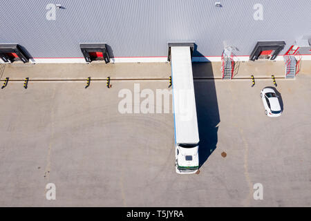 Aerial Side Shot of Industrial Warehouse Loading Dock where Many Truck with Semi Trailers Load/ Unload Merchandise Stock Photo