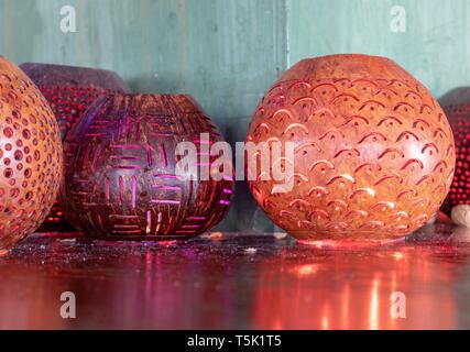 Colorful decorative candle bowls reflecting off the surface of a shiny wooden table top Stock Photo