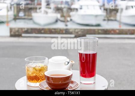 Tea served on a small round table in a selection of containers - cups and glasses and white teapot Stock Photo