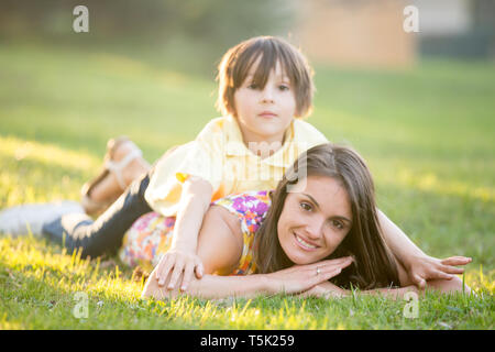 Beautiful family, mother, father and three kids, boys, having familly outdoors portrait taken on a sunny spring evening, beautiful blooming garden, su Stock Photo