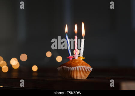 Candles in a cupcake for a holiday. The concept of a festive birthday card. Candles blow out, burning candles with space for text. Beautiful greeting Stock Photo