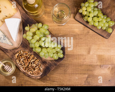 Top view of wolnuts next to fresh grapes on wooden plate in a vintage restaurant. Glas of white wine. Stock Photo