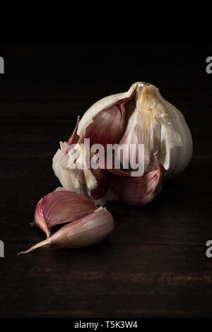Garlic bulb and cloves on dark board Stock Photo