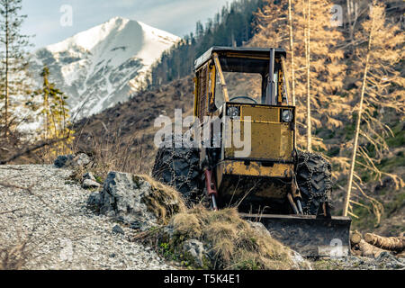 Bulldozer resting in high mountains after work, heavy machinery industry in woods, after work. Stock Photo
