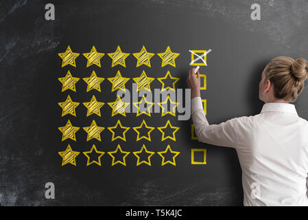 excellent five star customer feedback or client service rating with rear view of woman at blackboard Stock Photo