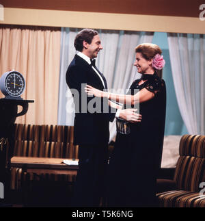 Der Schauspieler, Entertainer und Synchronsprecher Harald Juhnke posiert mit seiner Frau Chariklia Baxevanos in einem Wohnzimmer oder an einem Set, Deutschland 1970er. The actor, entertainer and voice actor Harald Juhnke poses with his wife Chariklia Baxevanos in a living room or on a set, Germany 1970s. Stock Photo