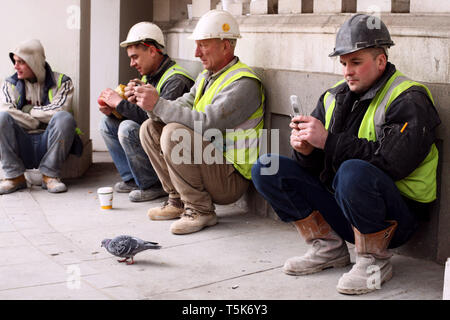Construction workers on their lunch break sitting down together and having a chat. London. 03.02.2010. Stock Photo
