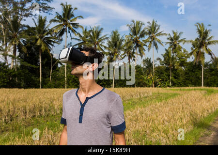 Young man wearing VR glasses in the tropical rice field Stock Photo