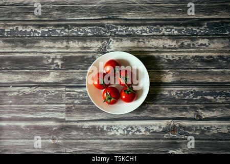 Tomatoes in a white circular bowl from top down in a dark wood background Stock Photo