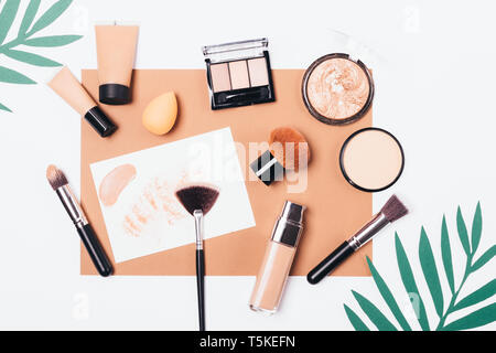 Summer cosmetics and tools to create smooth complexion and tan, flat lay composition. Foundation, powder, bronzer and makeup brushes, top view on whit Stock Photo