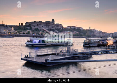 BUDAPEST / HUNGARY - 04.21.2019: Panoramic view of Buda Castle, with tourist boats on Danube river in the foreground. Stock Photo