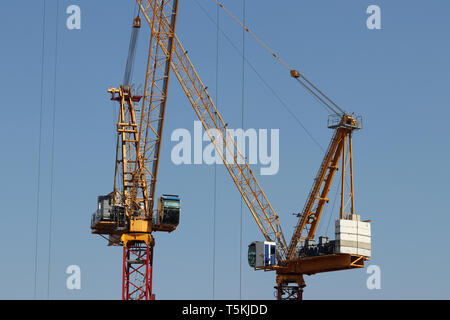 Construction cranes isolated on clear blue sky background. Concept of housing construction or heavy cargo loading work Stock Photo