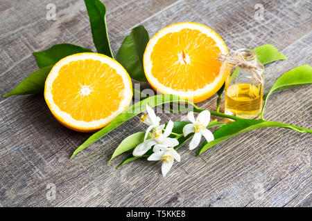 Juicy Orange cut in two parts and neroli, flowers of orange tree, on rustic wood background. The Orange blossom is the fragrant flower of the Citrus i Stock Photo