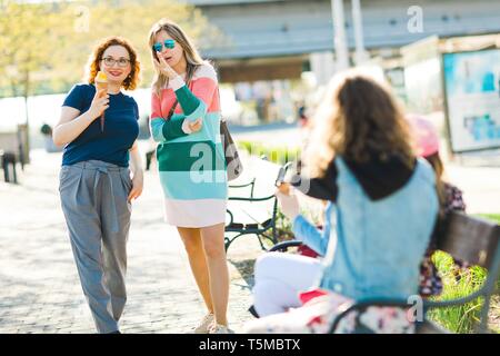 Two attractive women in the city chatting together about interesting places over the city. Stock Photo
