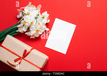 bouquet of daffodils, gift wrapping and a sheet of paper mockup with space for text Stock Photo