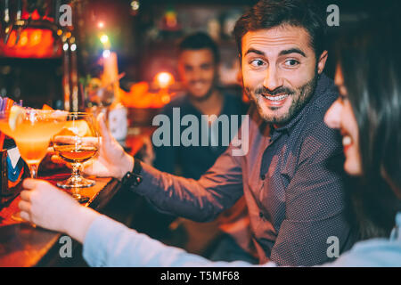 Happy friends having fun at cocktail bar - Young trendy people drinking cocktails and laughing together in a club - Party and nightlife concept Stock Photo