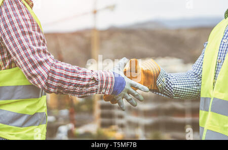 Close up builders hands making a deal - Workers on construction site reaching an agreement - Building, dealing, enginner industrial concept Stock Photo
