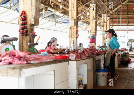 Two women talk over stacks of raw meat at a meat market in SaPa Vietnam, Asia Stock Photo