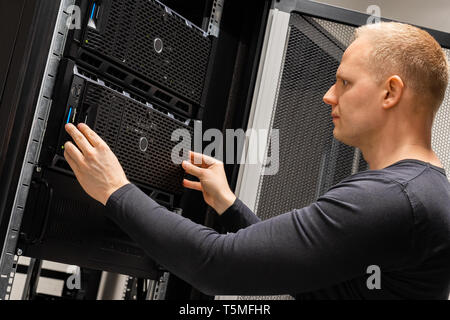 Male Technician Installing Servers In Enterprise Datacenter for Cloud Hosting Stock Photo