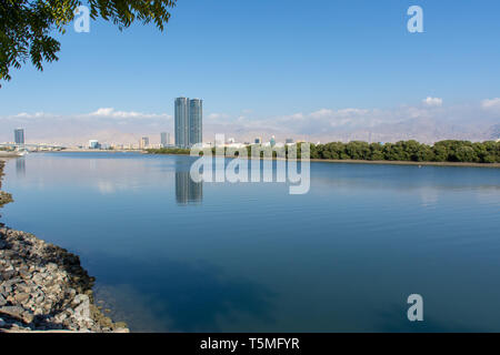 Ras al Khaimah View from the Corniche towards the Julphar Towers on the left, downtown, the crisp mountains in the late winter afternoon sun. Stock Photo