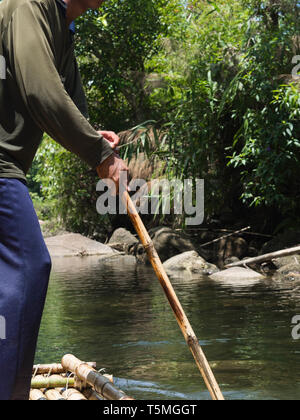 Undefined man drives a makeshift raft sailing along a river in the jungle Stock Photo