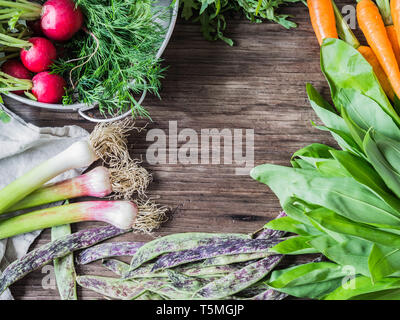 Fresh Spring vegetables and herbs frame on rustic wood background. Spring harvest of fresh vegetables. top view Stock Photo