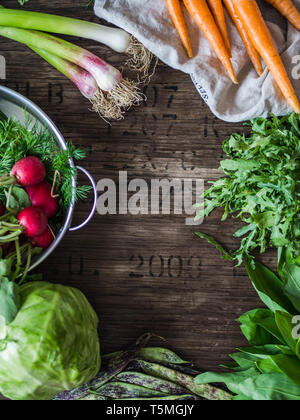 Fresh Spring vegetables and herbs frame on rustic wood background. Spring harvest of fresh vegetables. top view