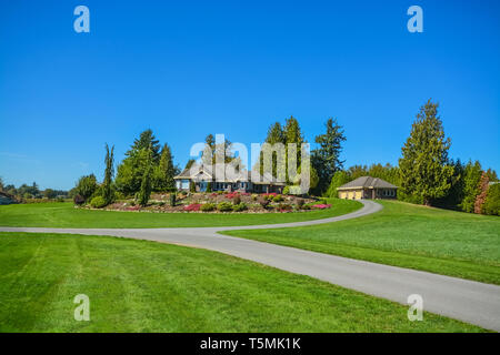 Asphalt road junction running over landscape with big farmer's house on the hill Stock Photo