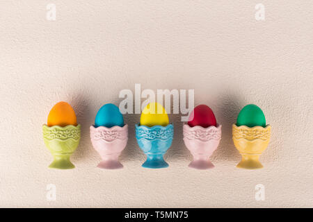 Ceramic egg-cups with colorful painted eggs arranged in a row Stock Photo