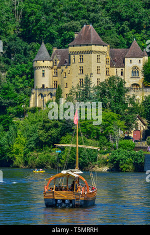 River boat (Gabarre) and Chateau de la Malartrie, at La Roque-Gageac in the Dordogne department in Nouvelle-Aquitaine, southwestern France. Stock Photo