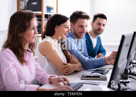 Businessman Pointing On Computer Screen While Talking With Her Colleague Stock Photo